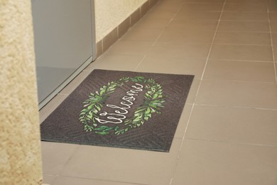 Photo of Beautiful doormat with word Welcome on floor near entrance