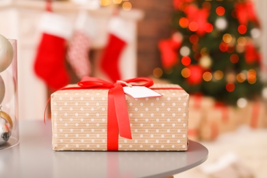 Photo of Gift box on table and Christmas tree in room