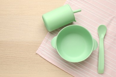 Photo of Set of plastic dishware on wooden background, top view with space for text. Serving baby food