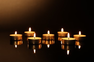 Burning candles on mirror surface in darkness