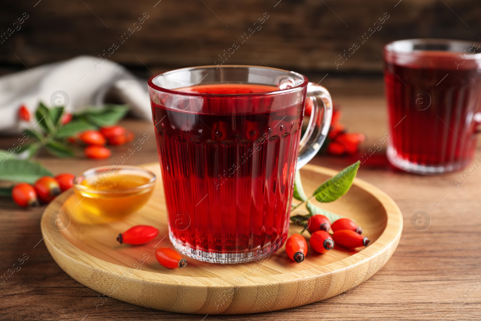 Photo of Fresh rose hip tea, honey and berries on wooden table