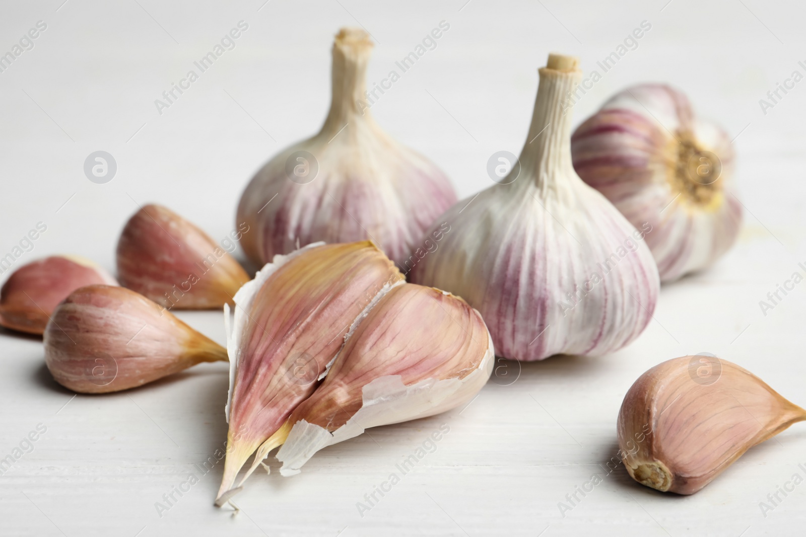 Photo of Fresh organic garlic on white wooden table, closeup