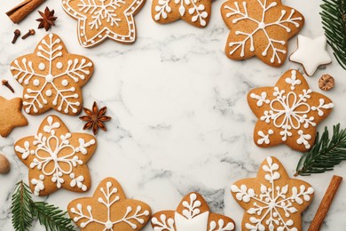 Frame made of tasty star shaped Christmas cookies with icing, spices and fir tree twigs on white marble table, flat lay. Space for text