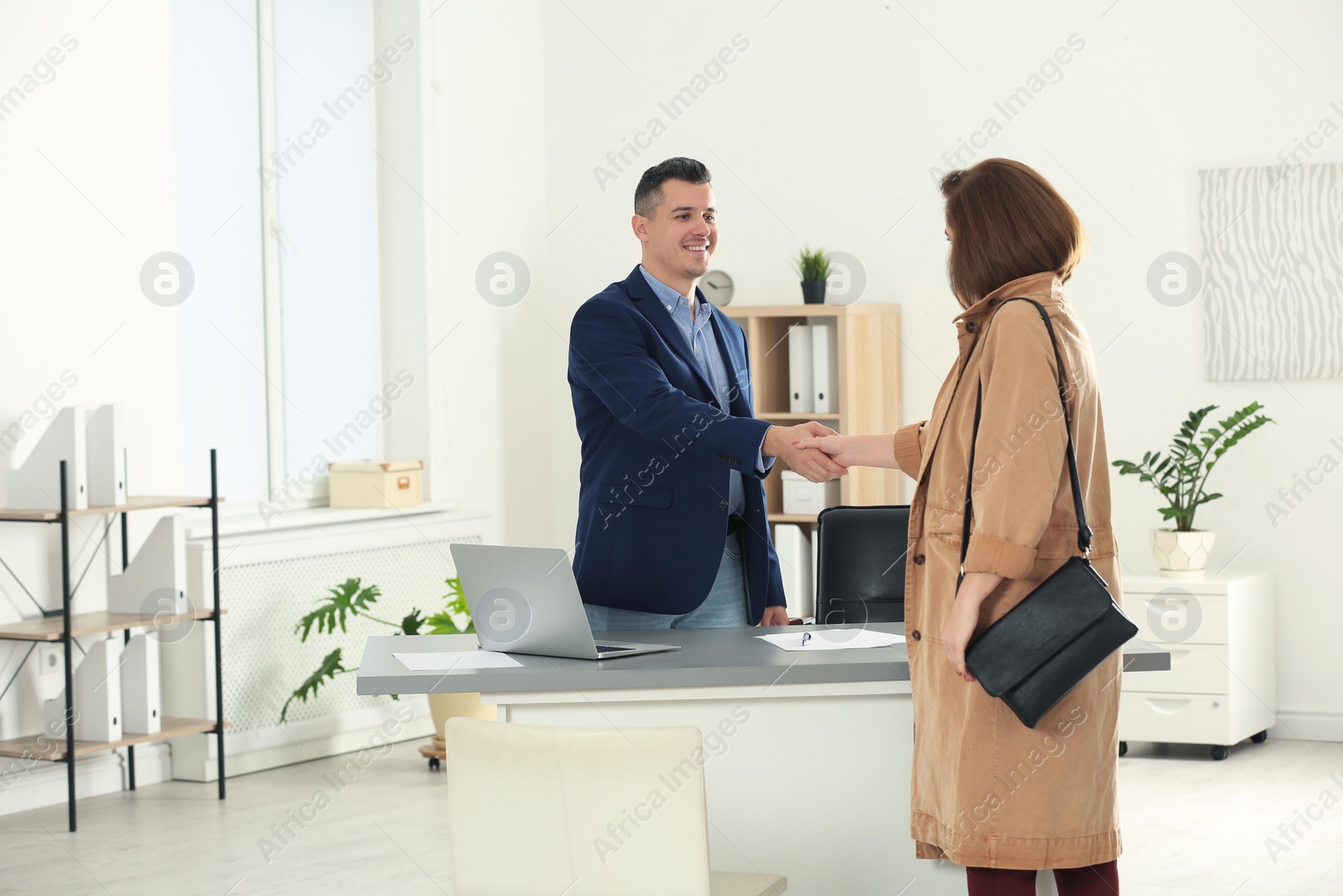 Photo of Human resources manager shaking hands with applicant after job interview in office