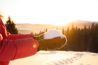 Woman holding pile of snow outdoors, closeup. Winter vacation