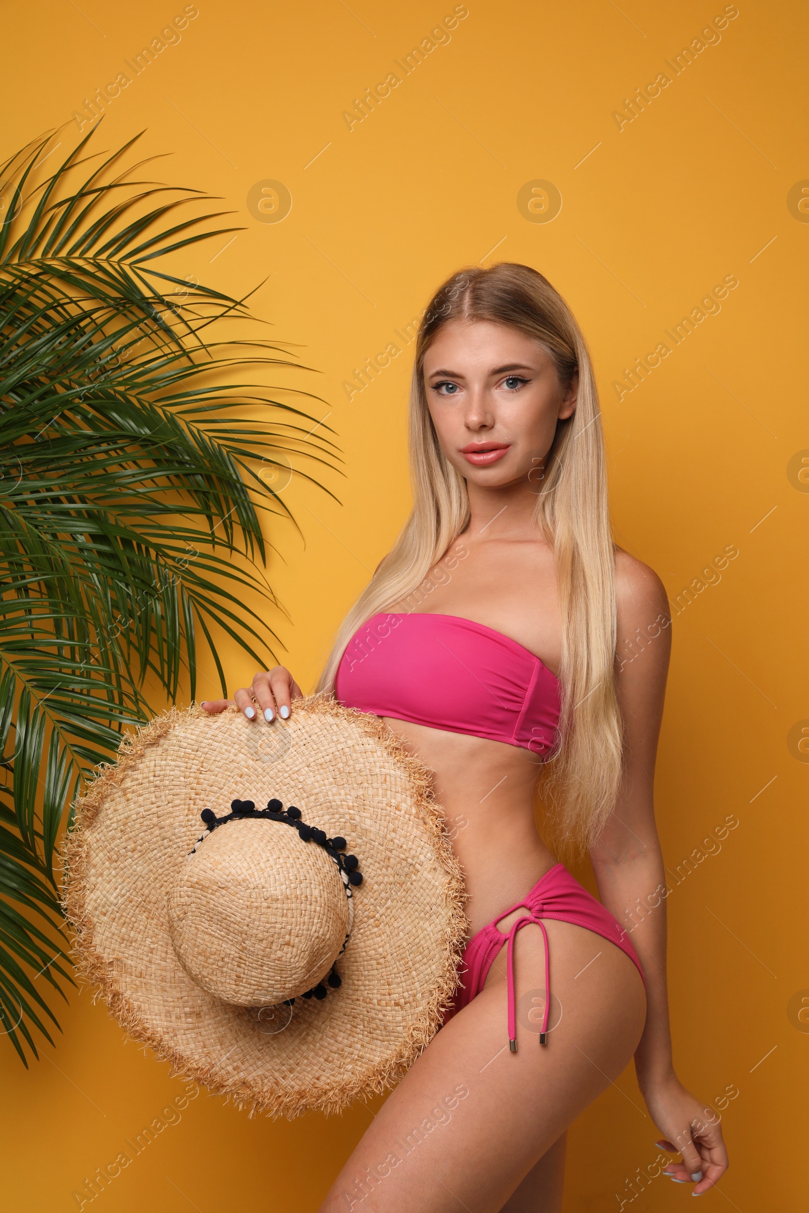 Photo of Pretty young woman wearing stylish bikini on orange background