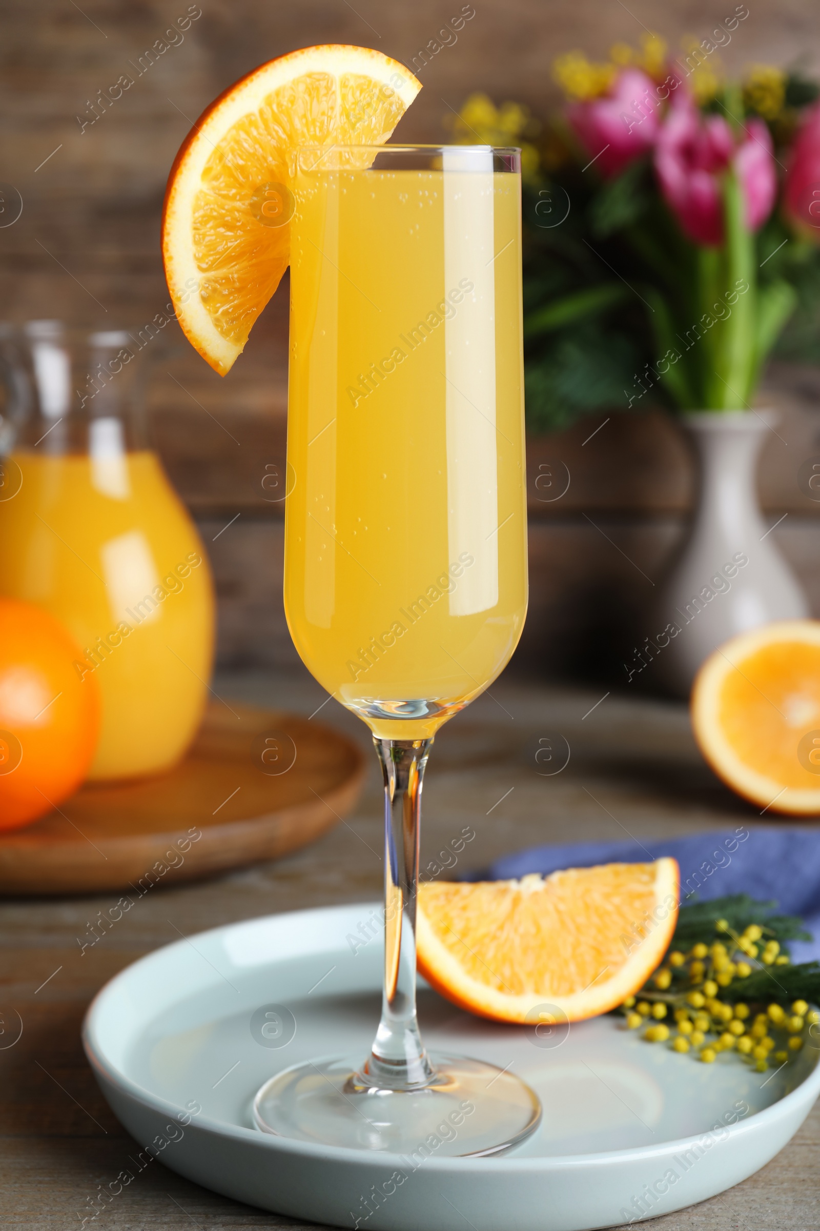 Photo of Glass of Mimosa cocktail with garnish on wooden table