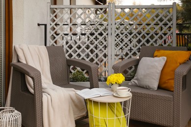 Different pillows, book and beautiful chrysanthemum flowers on garden furniture outdoors