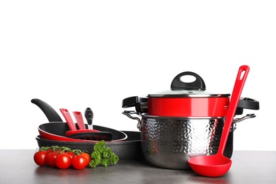 Photo of Set of clean cookware, utensils and vegetables on table against white background