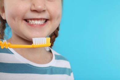 Photo of Little girl brushing teeth on color background, closeup. Space for text