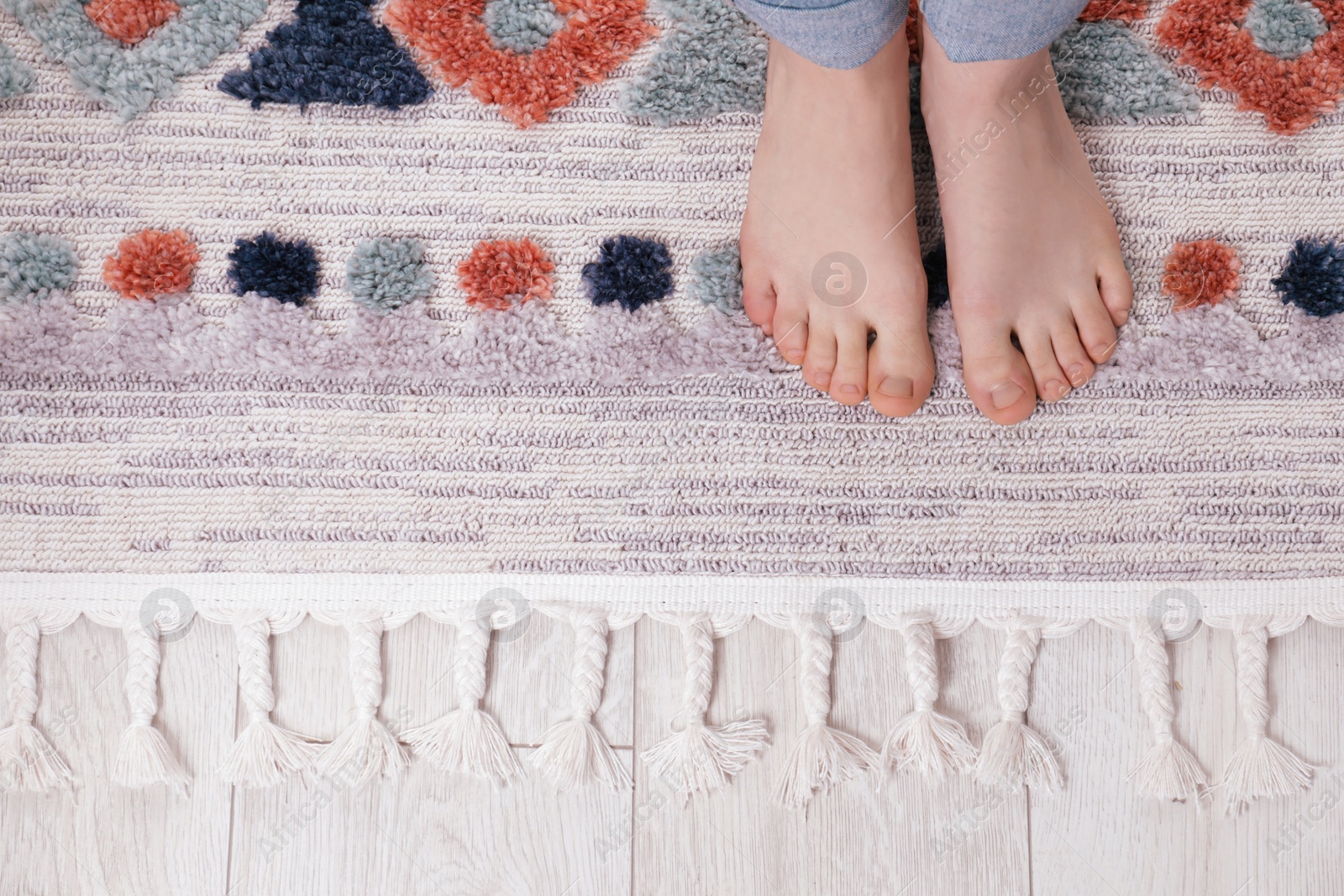 Photo of Woman standing on carpet with pattern at home, top view