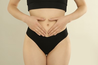 Photo of Gynecology. Woman in underwear making heart with her hands on light background, closeup