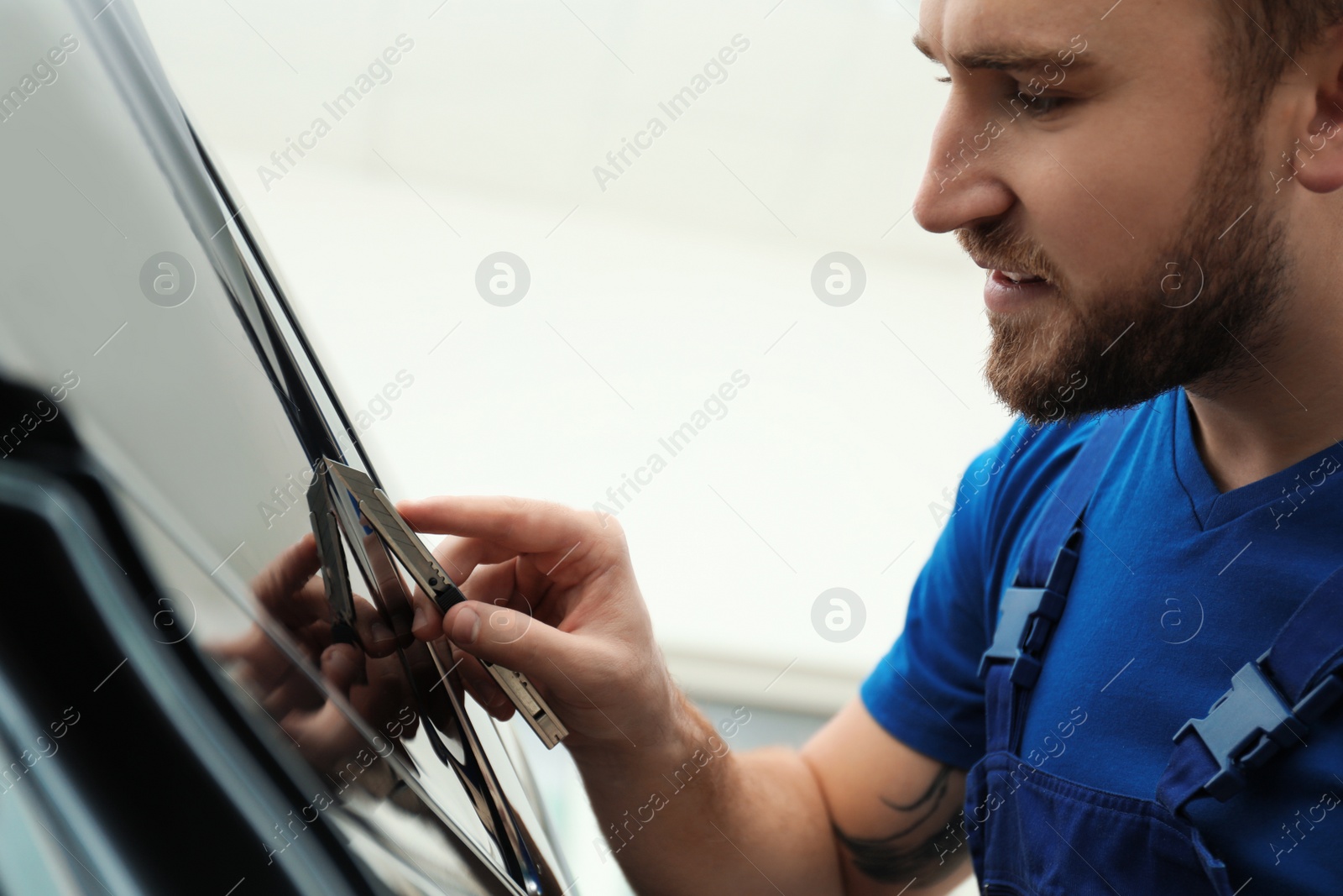 Photo of Worker tinting car window with foil in workshop