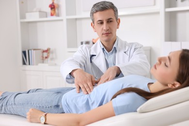 Photo of Gastroenterologist examining patient with stomach pain on couch in clinic