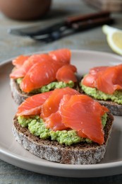 Delicious sandwiches with salmon and avocado on grey plate, closeup