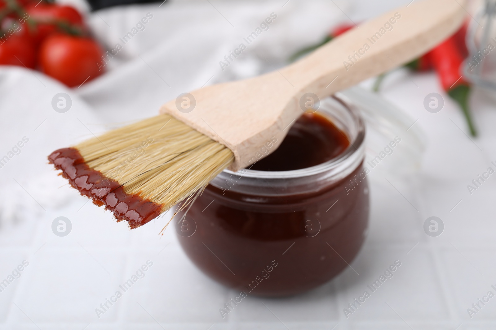 Photo of Marinade in jar and basting brush on white table, closeup