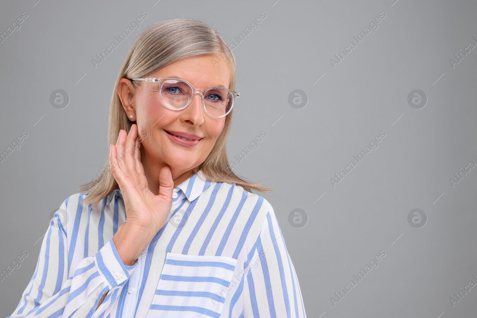 Photo of Portrait of beautiful middle aged woman in eyeglasses on light grey background, space for text