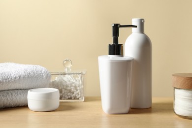 Different bath accessories on wooden table against beige background, closeup