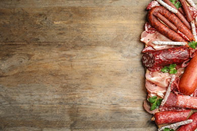 Photo of Different types of sausages with parsley on wooden table, top view. Space for text