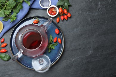 Photo of Flat lay composition with aromatic rose hip tea on black table. Space for text