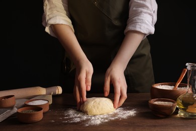 Photo of Woman making grissini at wooden table, closeup