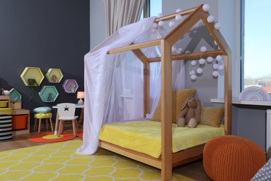 Photo of Stylish child room interior with comfortable house bed and toys