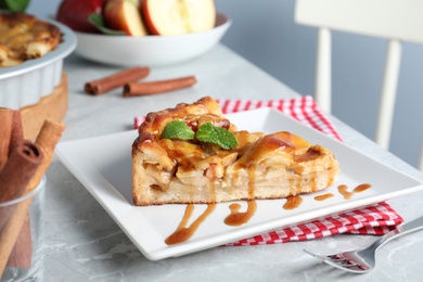 Slice of traditional apple pie served on light marble table