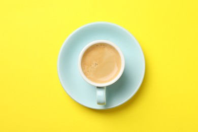 Aromatic coffee in cup on yellow background, top view