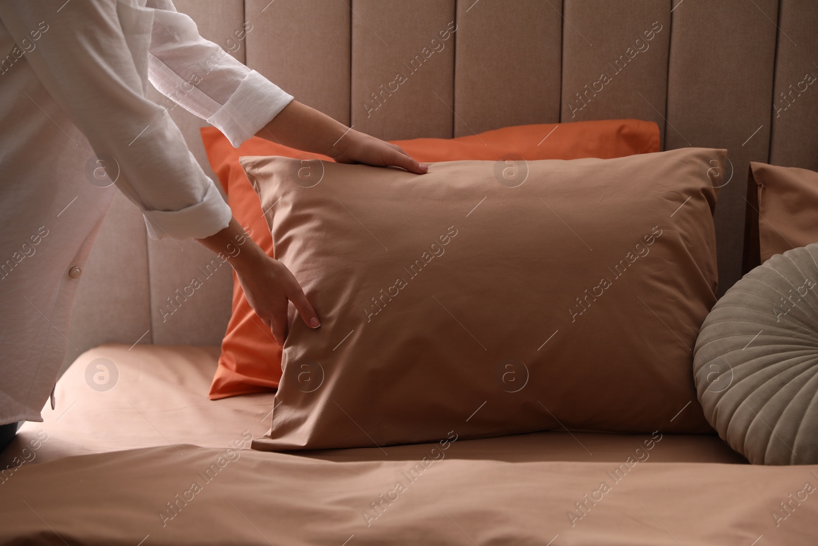 Photo of Woman making bed with stylish linens in room, closeup