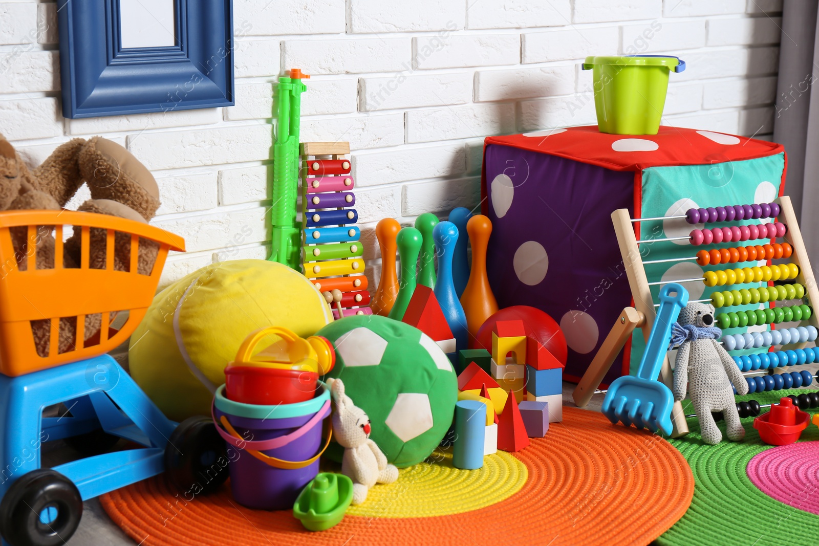 Photo of Different child toys on floor against brick wall