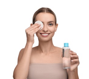 Smiling woman removing makeup with cotton pad and holding bottle on white background