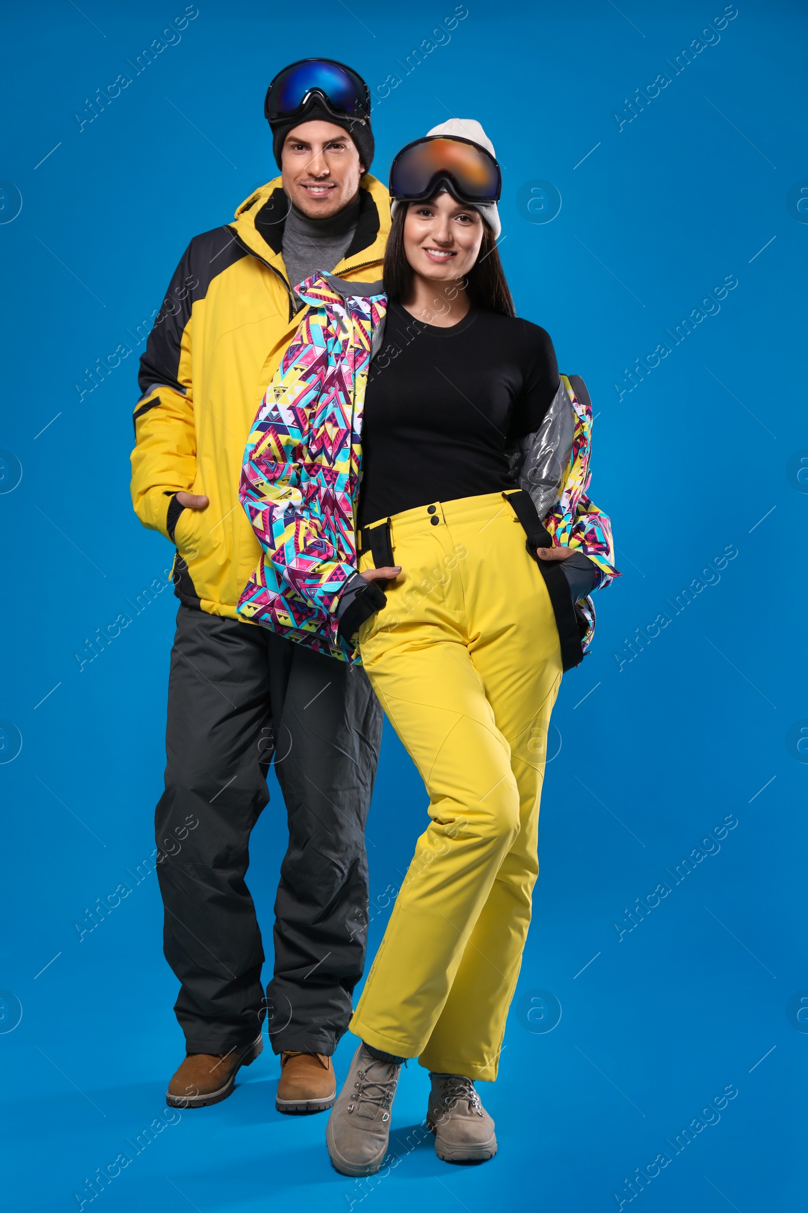 Photo of Couple wearing stylish winter sport clothes on light blue background