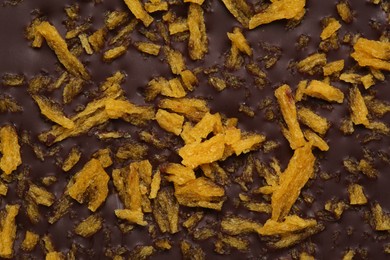 Photo of Chocolate bar with freeze dried fruits as background, closeup