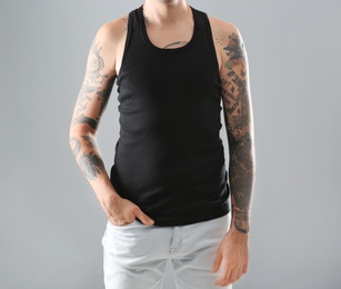 Photo of Young man with stylish tattoos on grey background