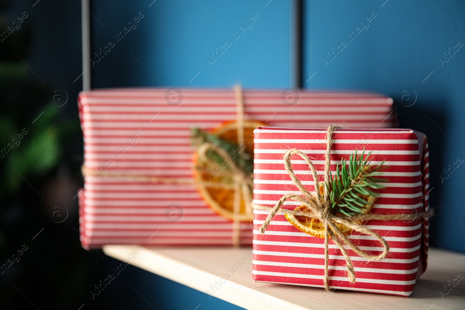 Photo of Beautifully wrapped gift boxes on rack indoors, space for text