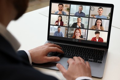 Image of Man having video chat with coworkers via laptop at white table, closeup