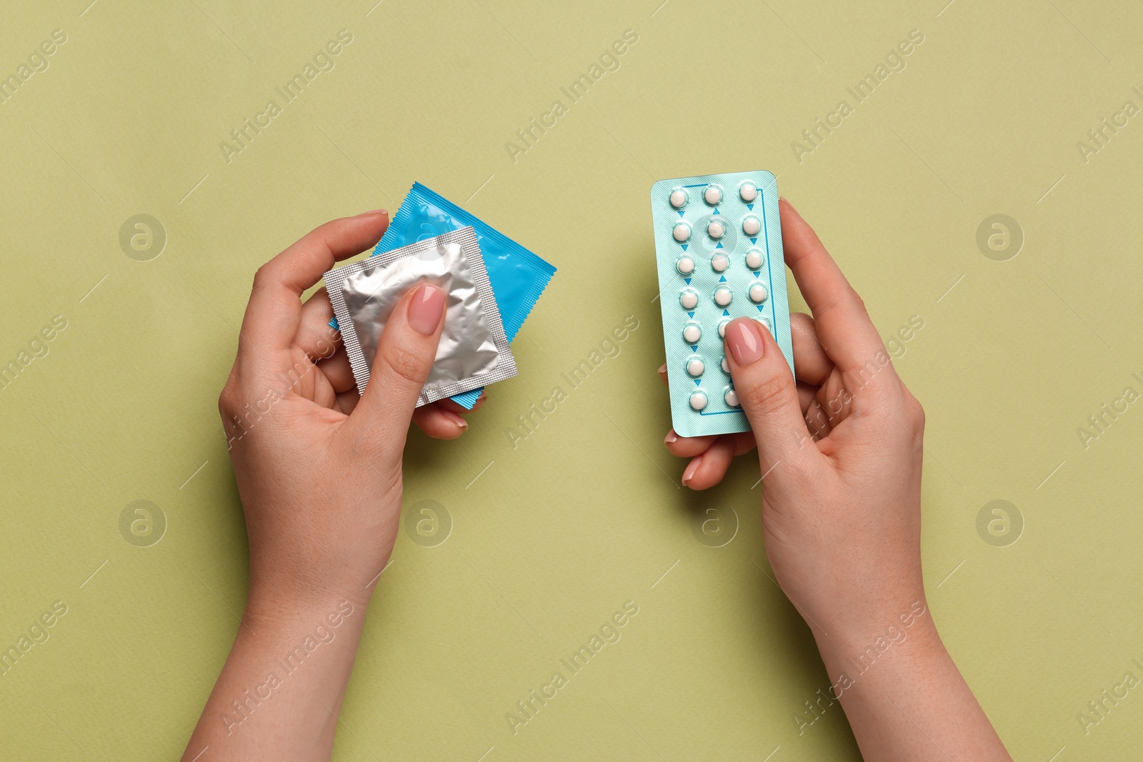 Photo of Woman with condoms and contraceptive pills on olive background, top view. Choosing birth control method