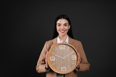 Photo of Businesswoman holding clock on black background. Time management