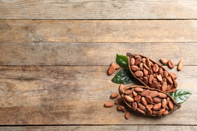 Cocoa pods and beans on wooden table, flat lay. Space for text