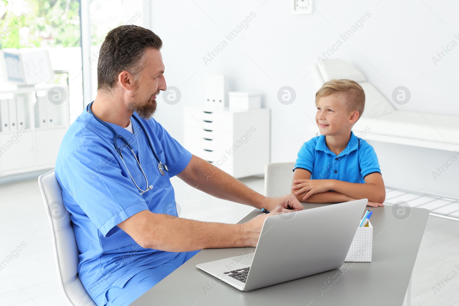 Photo of Male medical assistant consulting child in clinic