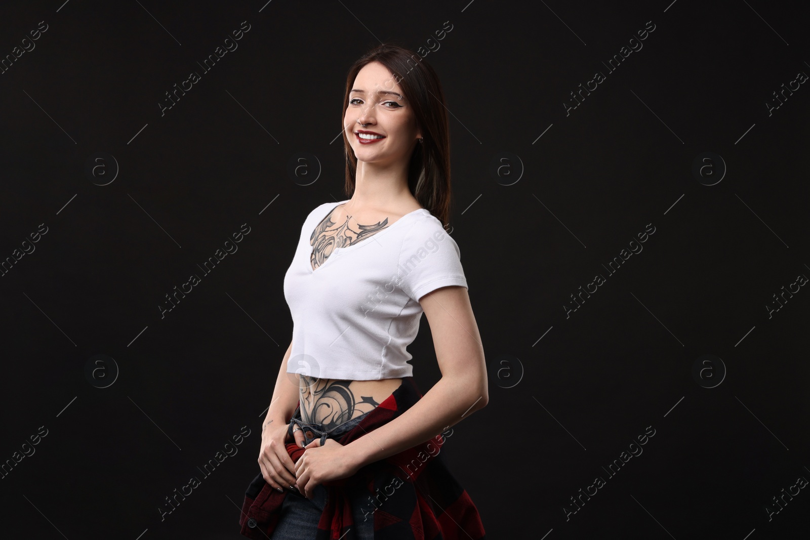 Photo of Portrait of smiling tattooed woman on black background. Space for text