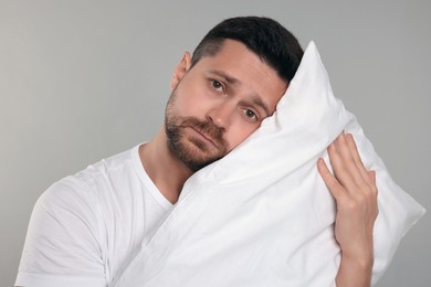 Sleepy man with pillow on grey background. Insomnia problem