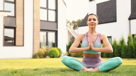 Photo of Woman practicing morning yoga at backyard. Healthy lifestyle