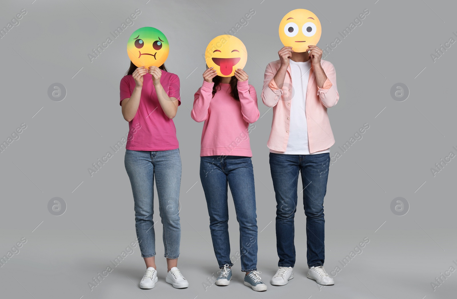 Photo of People covering faces with emoticons on grey background