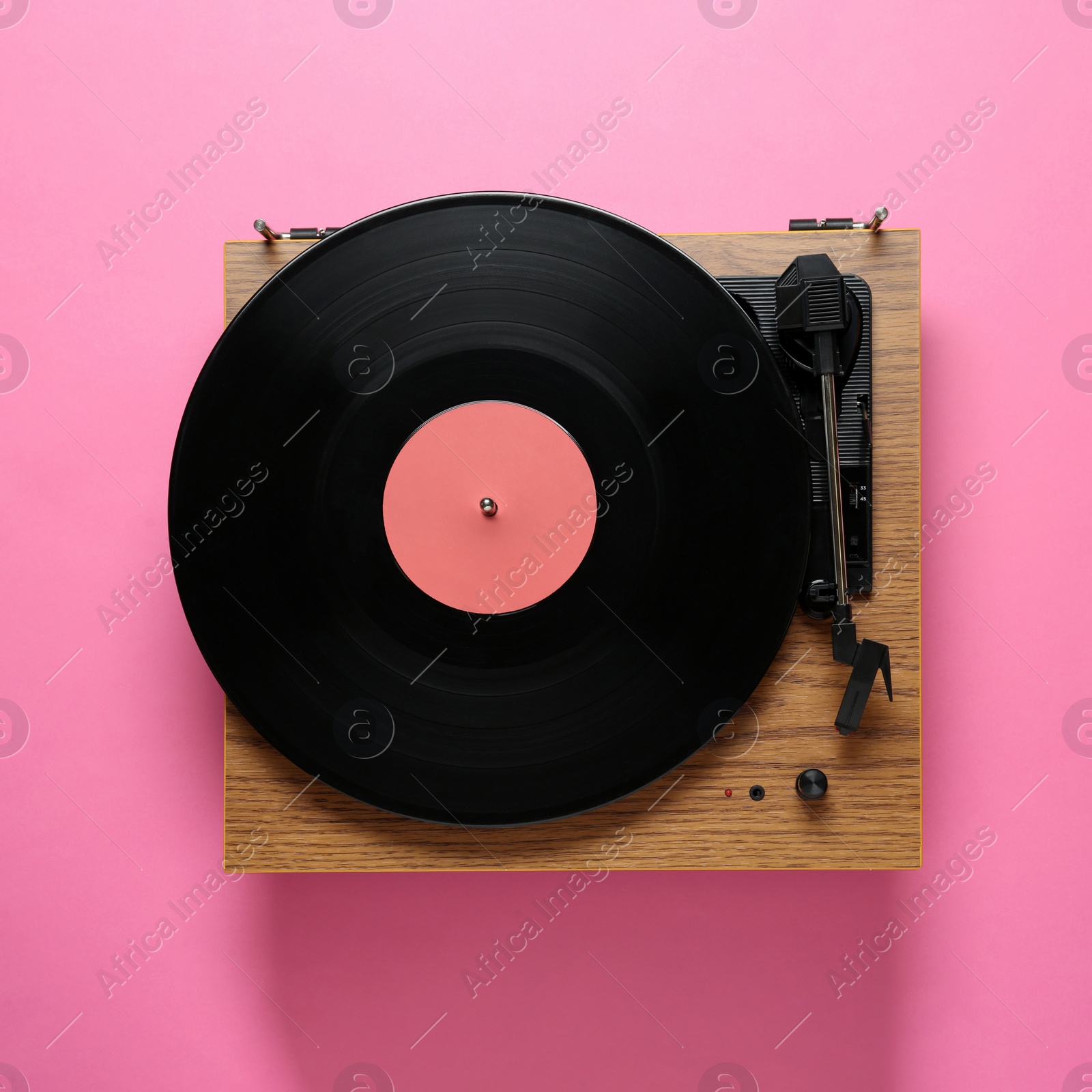 Photo of Modern turntable with vinyl record on pink background, top view