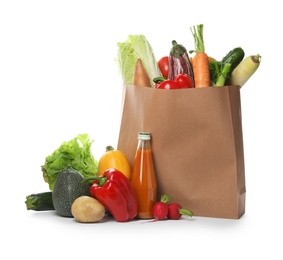 Paper bag with fresh vegetables and bottle of juice on white background