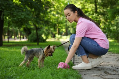 Photo of Woman picking up her dog's poop from green grass in park