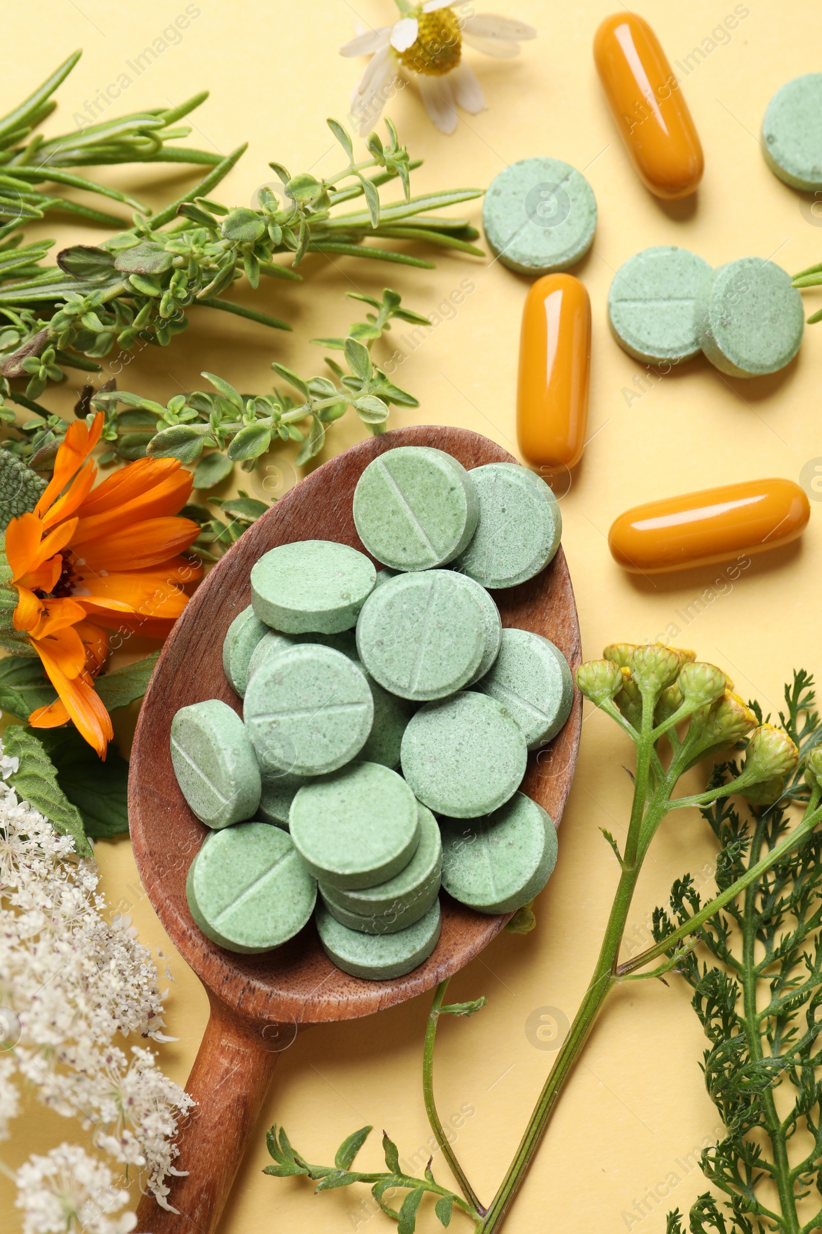 Photo of Different pills, herbs and flowers on pale orange background, flat lay. Dietary supplements