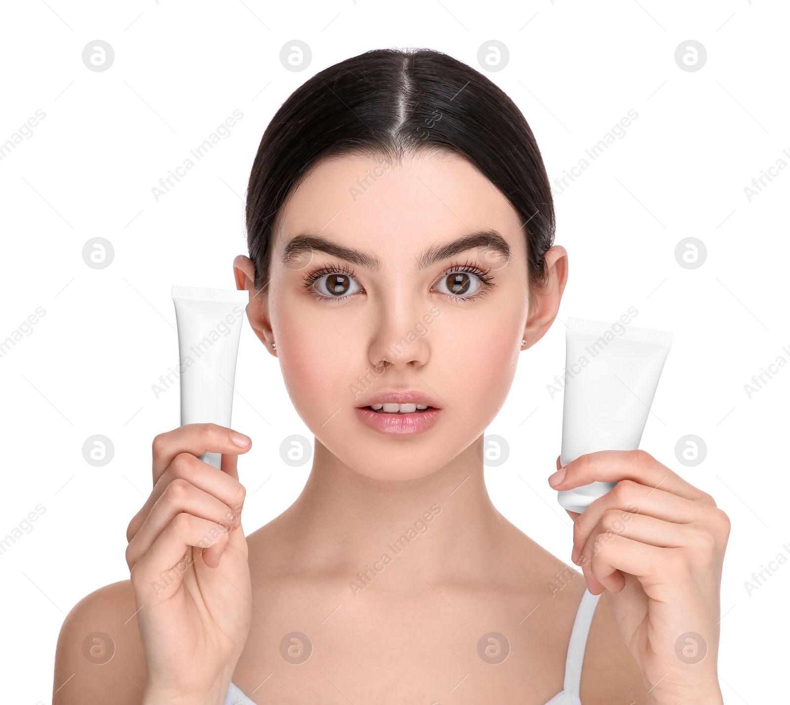 Photo of Teenage girl holding tubes of foundation on white background