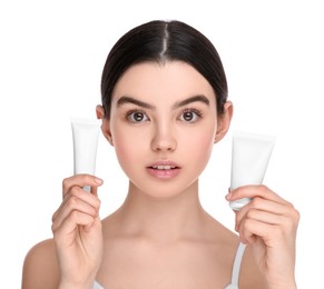 Teenage girl holding tubes of foundation on white background